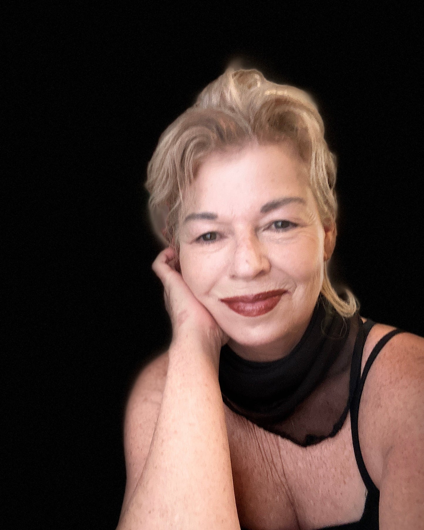 Maya Britan artist painter psychic reader Woman with blonde hair and a black top against a black background