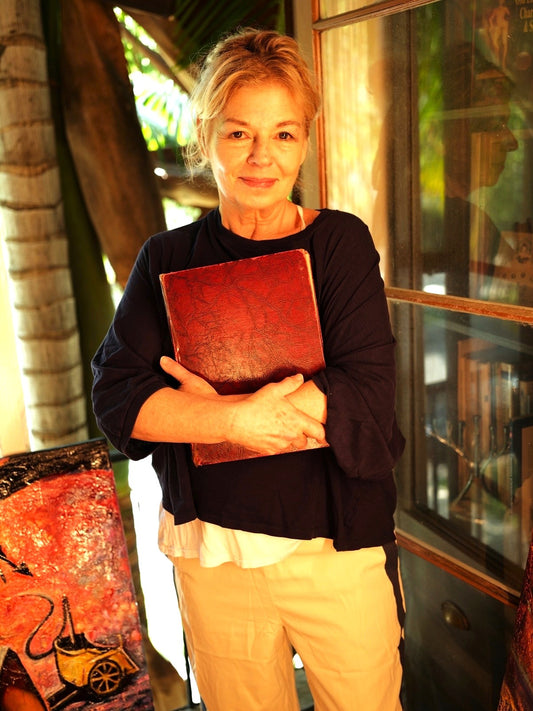Woman holding a red book in an indoor setting with warm lighting