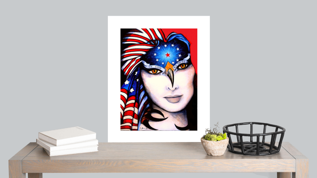 Framed artwork of a stylized face with colorful design on a table against a gray wall.