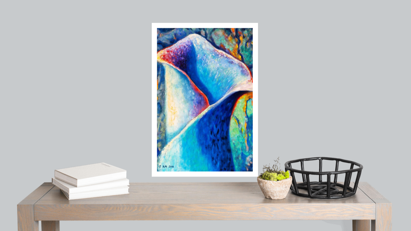 Framed abstract art piece on a wooden table with books and a basket against a gray wall.